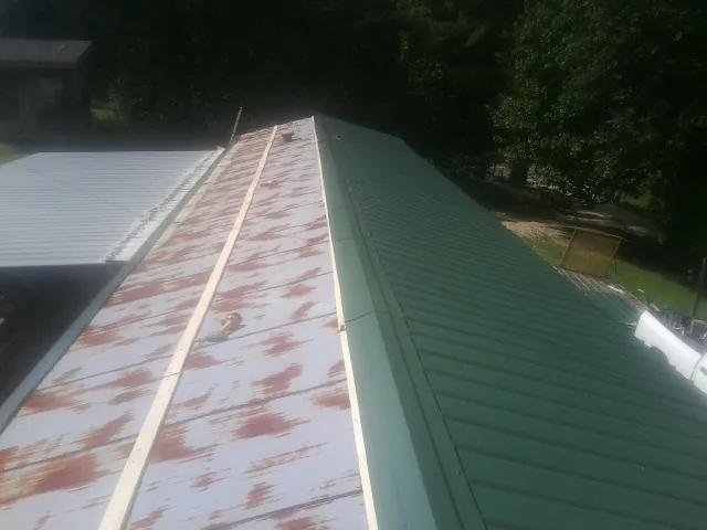 Old rusted panels beside newly installed green metal roofing — Wind Damage Roof Repair by Roofing Brothers in Fort Madison