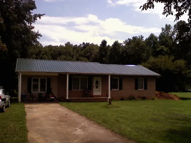 Dark green metal roof on a brick ranch with a covered porch in Fort Madison