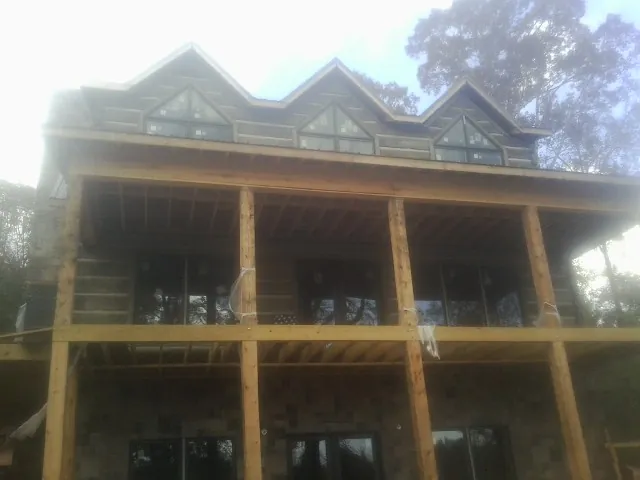 Dormers and porch framing on a large log home under construction — Roof Coating work by our crew in Fort Madison