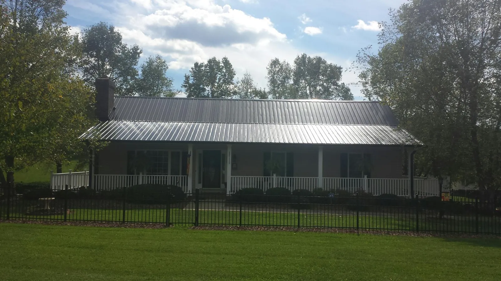 Gray metal roof on a brick ranch with a full width front porch — Gutter Guard Installation work by our crew in Fort Madison