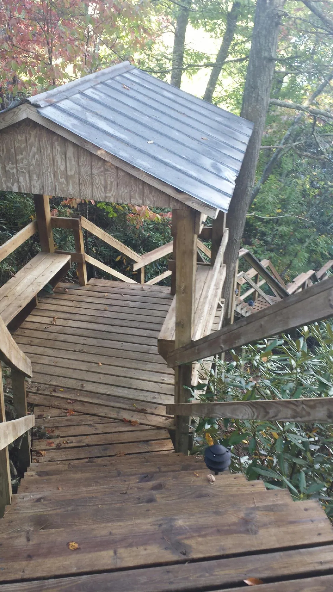 Metal roofed shelter over wooden steps on a wooded walkway — Skylight Repair & Installation work by our crew in Fort Madison