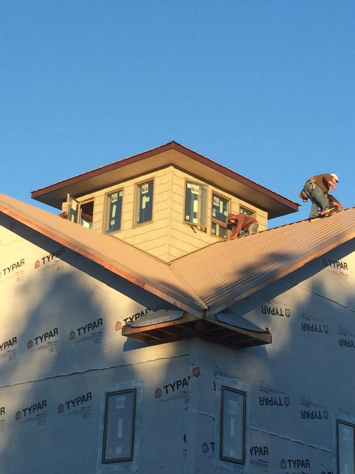 Roofers working around a rooftop cupola on a new metal roof at sunset — Roof Waterproofing in Fort Madison by Roofing Brothers